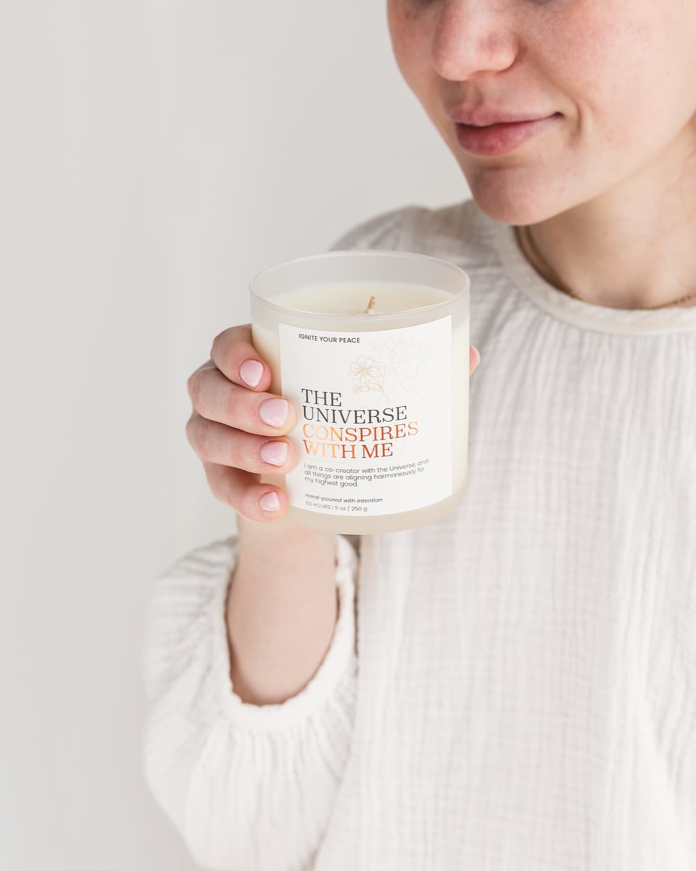 A woman cradling a warm Ignite Your Peace candle