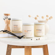 Three candles on a white surface with wooden legs, featuring motivational phrases.