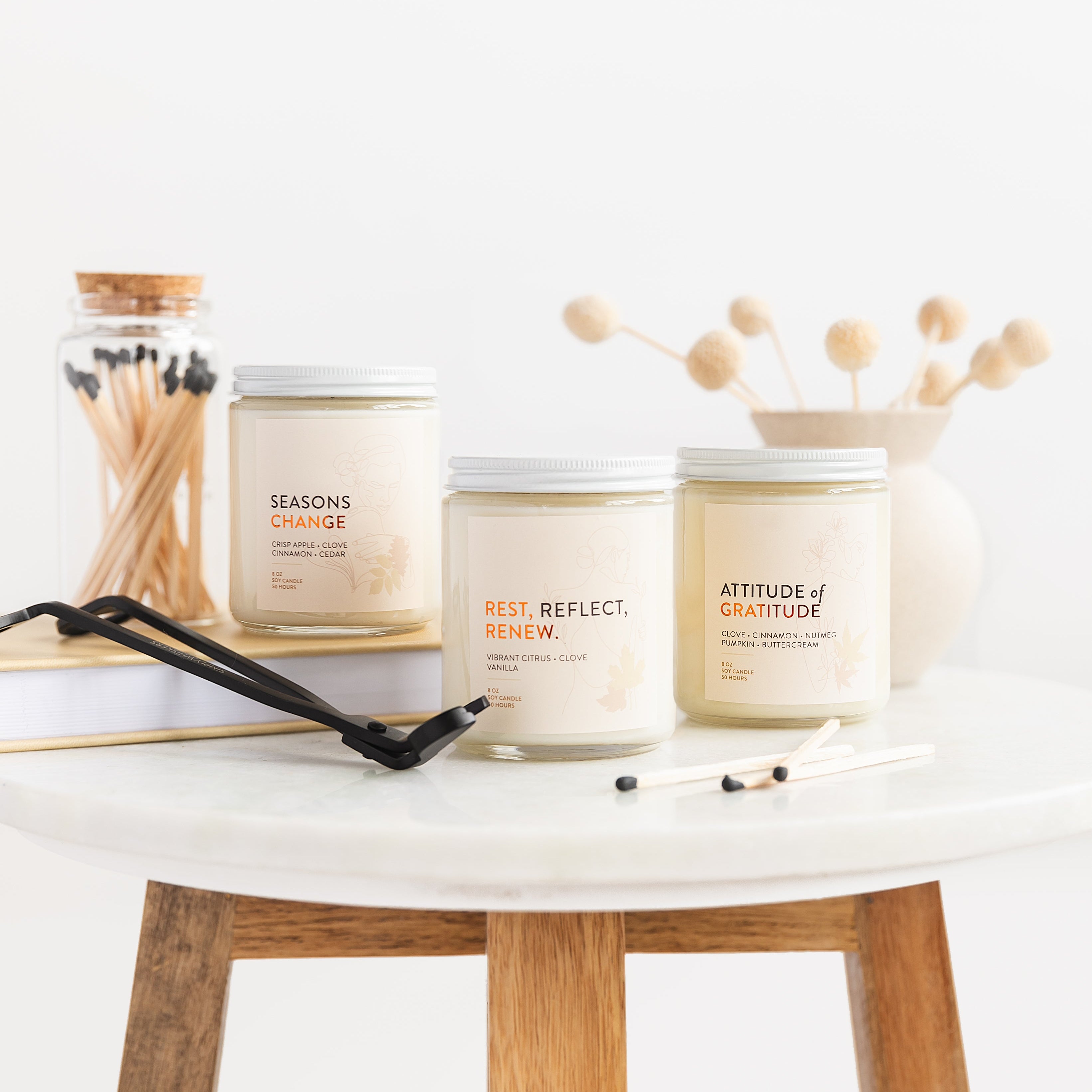Three candles on a white surface with wooden legs, featuring motivational phrases.